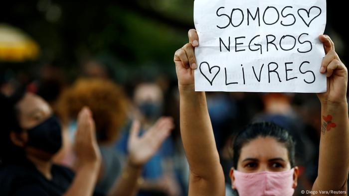 Manifestante de máscara carrega cartaz com os dizeres Somos negros livres Manifestante de máscara carrega cartaz com os dizeres Somos negros livres