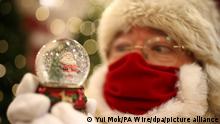 12.10.2020, Großbritannien, London: Ein als Weihnachtsmann verkleideter Mann hält in einer Filiale des Kaufhauskette Selfridges mit Mund-Nasen-Schutz eine Schneekugel in den Händen. Das diesjährige Thema wurde unter dem Motto «Once Upon A Christmas» enthüllt. Foto: Yui Mok/PA Wire/dpa +++ dpa-Bildfunk +++ |