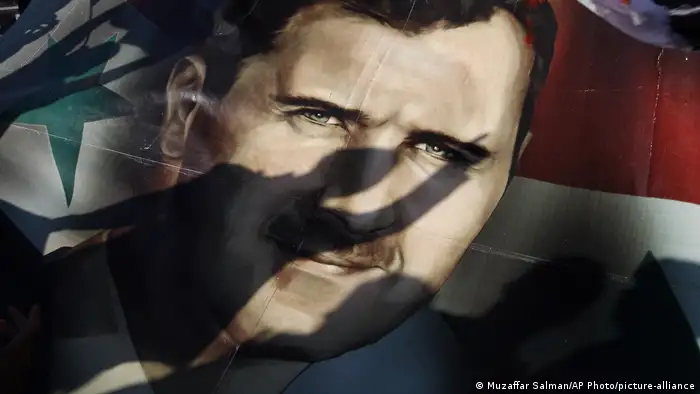 Syrien Ein Schatten fällt auf die Fahne mit dem Portait von Präsident Bashar Assad