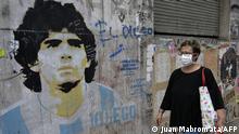A woman walks by a graffiti depicting Argentine former football star Diego Maradona during the lockdown imposed by the government against the spread of the new coronavirus, COVID-19, in Buenos Aires, Argentina, on April 22, 2020. (Photo by JUAN MABROMATA / AFP)