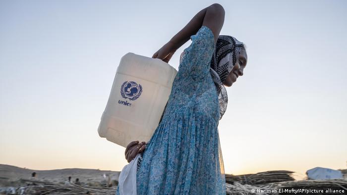 A Tigray woman who fled the conflict in Ethiopia's Tigray region, carries water on her back