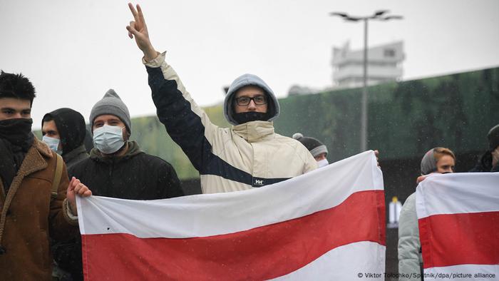 Протестующие держит бело-красно-белый флаг в Минске