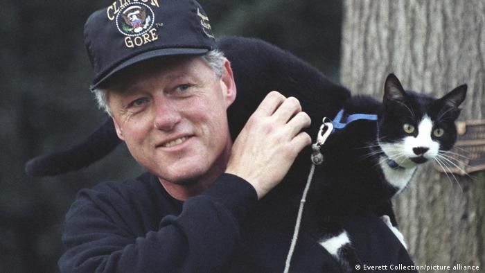 President Clinton wearing a baseball cap with Socks the Cat perched on his shoulder.