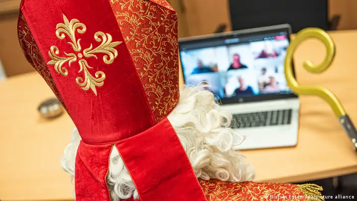 Man dressed as St Nicholas sits with mitre and crosier in front of a laptop in a video conference, Essen, Germany (dpa)