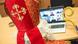 Man dressed as St Nicholas sits with mitre and crosier in front of a laptop in a video conference, Essen, Germany (dpa)