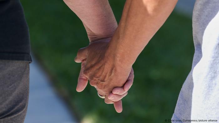 Photo of two people holding hands, one is an Alzheimer's patient