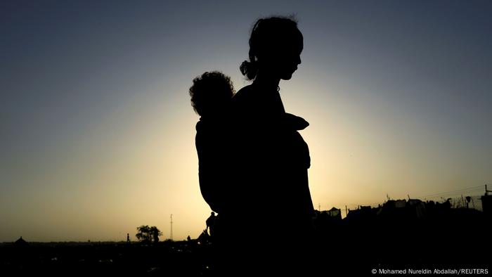 An Ethiopian woman carries her child near the Setit River on the Sudan-Ethiopia border