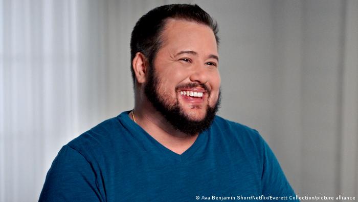 Chaz Bono, bearded and laughing in a blue sweatshirt.