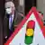 Michel Barnier walks behind a sign with a traffic light on it 
