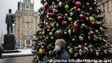 A man wears a protective face masks as he walks past a Christmas tree in the Red Square in central Moscow on December 1, 2020, as Russia confirmed 26 402 new daily Covid-19 cases including 6 524 in Moscow and 3 697 for Saint Petersburg. (Photo by Dimitar DILKOFF / AFP) (Photo by DIMITAR DILKOFF/AFP via Getty Images)