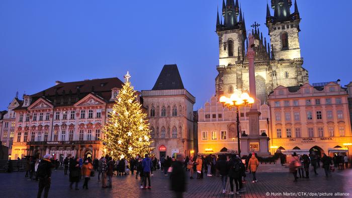 People in front of festively lit Christmas fir tree in Old Town Square in Prague, Czech Republic