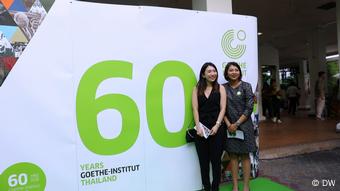 60 Jahre Goethe-Institut in Thailand, jubelt den Gästen vor einem Jubiläumsplakat zu
