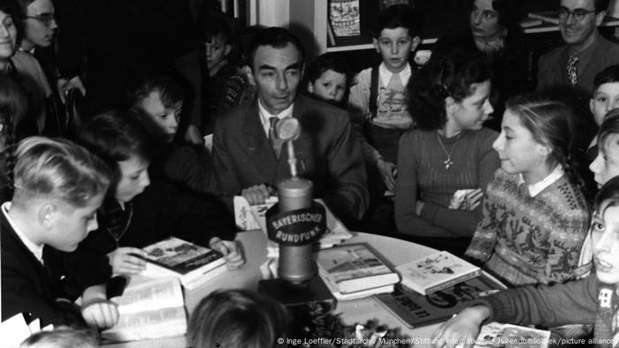 Deutschland Erich Kästner bei einer Lesung, umrundet von Jugendlichen 