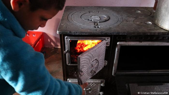 A boy adds wood to a burning stove