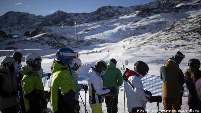 Ski enthusiasts with protective face mask queue for the ski lift