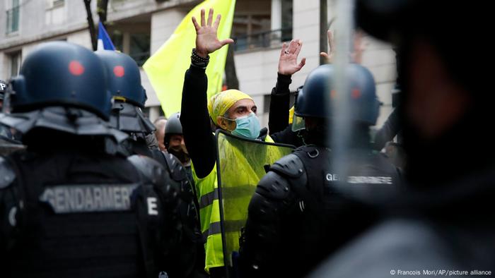 A protester wearing a yellow vest holds up his hands during a demonstration against a new security law in Paris