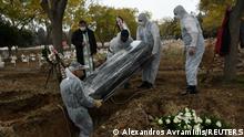 Pallbearers in personal protective equipment (PPE) place a coffin inside a grave, in a designated cemetery area for patients who died from the coronavirus disease (COVID-19), in Thessaloniki, Greece, December 3, 2020. Picture taken December 3, 2020. REUTERS/Alexandros Avramidis