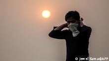 A man covers his face as he walks at a park during sunset amid heavy smoggy conditions in New Delhi on November 9, 2020. (Photo by Jewel SAMAD / AFP)