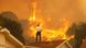 A man stands on the roof of a house, looking at a fire A man stands on the roof of a house, looking at a fire