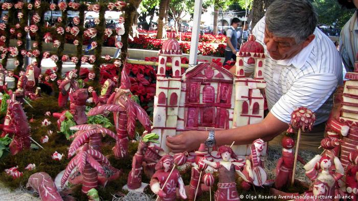A man tending to his display of a church and figures made of carved radishes
