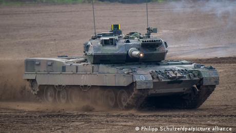 A German army tank drives along a barren landscape