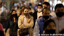 A woman wearing a protective face mask queue to cross a street, as the coronavirus disease (COVID-19) outbreak continues, in Mexico City, Mexico December 11, 2020. REUTERS/Gustavo Graf