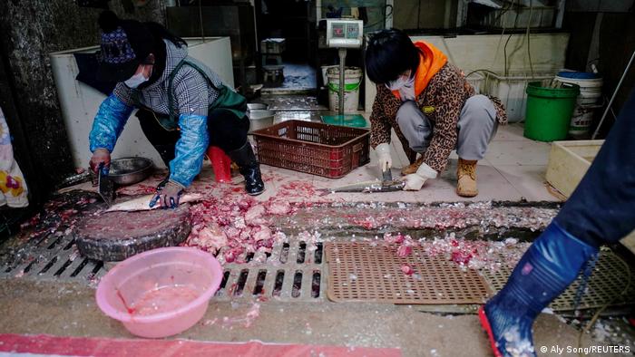 Люди чистят и разделывают рыбу прямо на полу и дренажных решетках на рынке