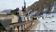 This photo taken from a video released by Azerbaijan's Defense Ministry on Wednesday, Nov. 25, 2020, shows Azerbaijan's army soldiers sitting atop of their military vehicle o a road in Kalbajar region of Azerbaijan. The Kalbajar district bordering Armenia, which houses one of the two roads linking Nagorno-Karabakh and the neighbouring country and has strategic significance for Armenians and Azeris, is due to be handed over to Azerbaijan according to a Russia-brokered cease-fire agreement between two countries in the long-running conflict over the separatist territory. (Azerbaijan's Defense Ministry via AP)