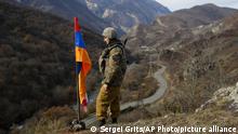 An ethnic Armenian soldier stands guard next to Nagorno-Karabakh's flag atop of the hill near Charektar in the separatist region of Nagorno-Karabakh at a new border with Kalbajar district turned over to Azerbaijan, Wednesday, Nov. 25, 2020. The Azerbaijani army has entered the Kalbajar region, one more territory ceded by Armenian forces in a truce that ended deadly fighting over the separatist territory of Nagorno-Karabakh, Azerbaijan's Defense Ministry said Wednesday. The cease-fire, brokered by Russia two weeks ago, stipulated that Armenia hand over control to Azerbaijan of some areas its holds outside Nagorno-Karabakh's borders. (AP Photo/Sergei Grits)