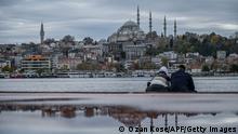 A couple sits on the deserted shore of Golden horn near Karakoy in Istanbul during a week-end curfew aimed at curbing the spread of the Covid-19 pandemic caused by the novel coronavirus, on December 12, 2020. - Under the new restrictions beginning from December 1, a curfew will be imposed on weekdays from 9:00 pm. to 5:00 am. Over the weekend the lockdown will last from 9:00 pm Friday until 5:00 am on Monday. (Photo by Ozan KOSE / AFP) (Photo by OZAN KOSE/AFP via Getty Images)