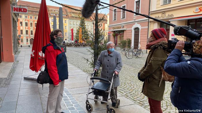Two women with masks covering only their mouths being interviewed by DW in Bautzen's empty pedestrian area