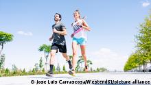 Mid adult couple running on road against blue sky during sunny day || Modellfreigabe vorhanden / Mindestpreis 20 Euro 