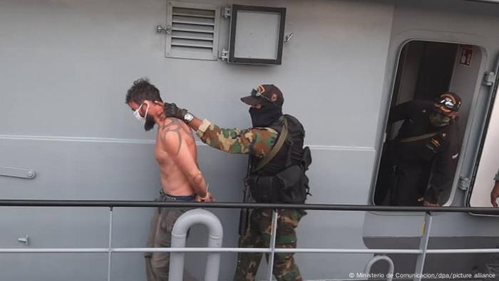 Un soldado lleva detenido a un hombre en Macuto, Venezuela.