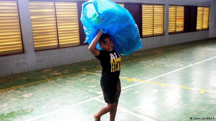A Fijian boy carries a bag to a temporary shelter