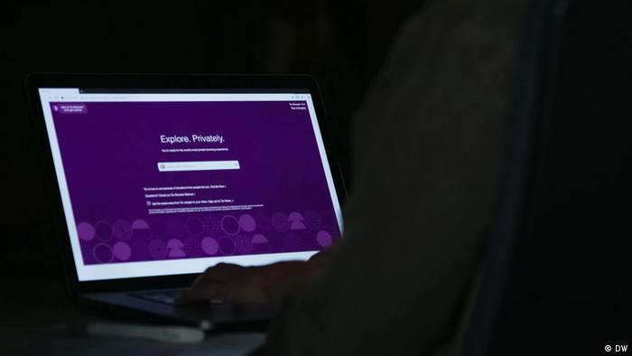 Ein Mensch sitzt im Dunklen und öffnet eine Webseite mit dem Tor-Browser. 