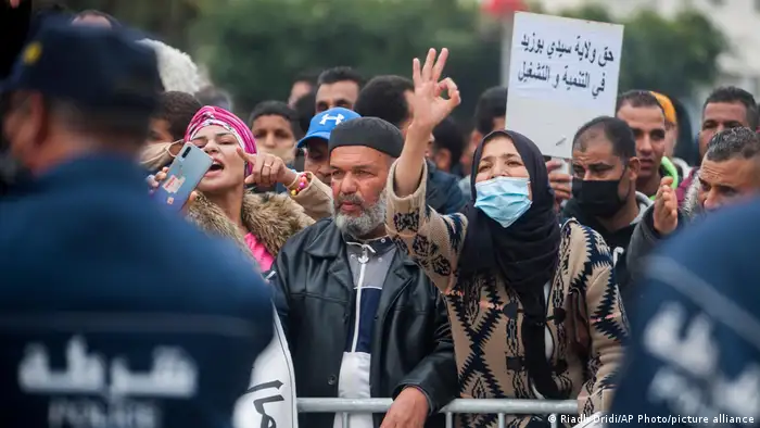 A crowd stands behind a barrier during a protest in Tunisia.