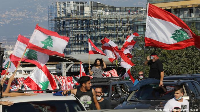Beirut locals in cars, wave flags, as they mark the one-year anniversary of Lebanese anti-government protests.