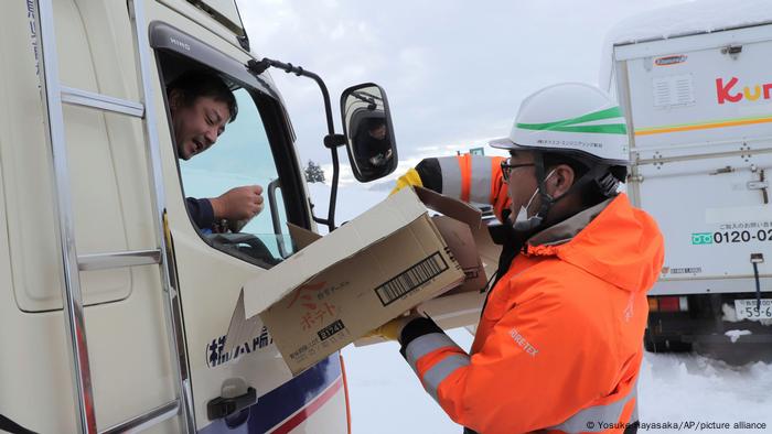 A man hands food to a truck driver 