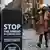 Passers-bz in London's Covent Garden walk past a sign that reads "Stop the spread of the coronavirus"