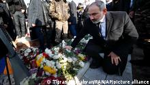 Armenian Prime Minister Nikol Pashinyan kneels at a grave of a killed soldier during a march of remembrance of the heroes killed in a war over the Nagorno-Karabakh region, in Yerevan, Armenia, Saturday, Dec. 19, 2020. Both opponents and supporters of Armenia's prime minister rallied Saturday as the nation paid tribute to the thousands who died in fighting with Azerbaijan over the region of Nagorno-Karabakh. Critics demanded that the leader resign and tried to pelt him with eggs. (Tigran Mehrabyan/PAN Photo via AP)