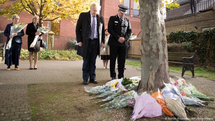 Boris Johnson und der Polizeichef von Essex, Ben-Julian Harrington, verneigen sich vor niedergelegten Blumensträußen Boris Johnson und der Polizeichef von Essex, Ben-Julian Harrington, verneigen sich vor niedergelegten Blumensträußen