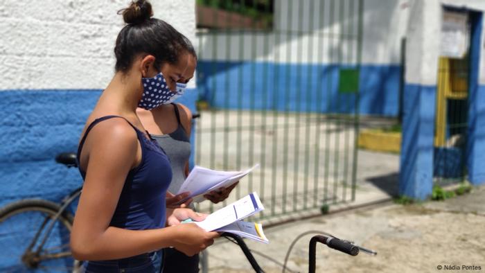 Meninas de máscara diante de escola