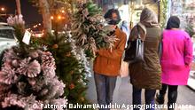 TEHRAN, IRAN - DECEMBER 22: A man carrying a Christmas tree walks past Christmas-themed window displays in a neighborhood with a large Christian population in Tehran, Iran, on December 22, 2020. Fatemeh Bahrami / Anadolu Agency