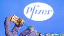 FILE PHOTO: A woman holds a small bottle labeled with a Coronavirus COVID-19 Vaccine sticker and a medical syringe in front of displayed Pfizer logo in this illustration taken, October 30, 2020. REUTERS/Dado Ruvic/File Photo