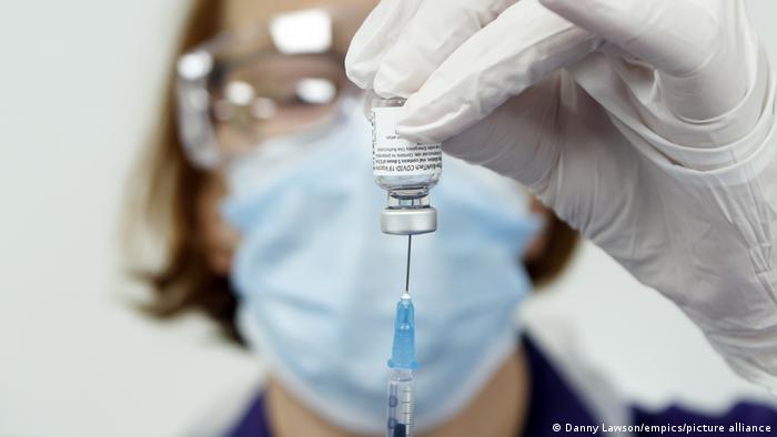 Врач наполняет шприц вакциной от коронавируса