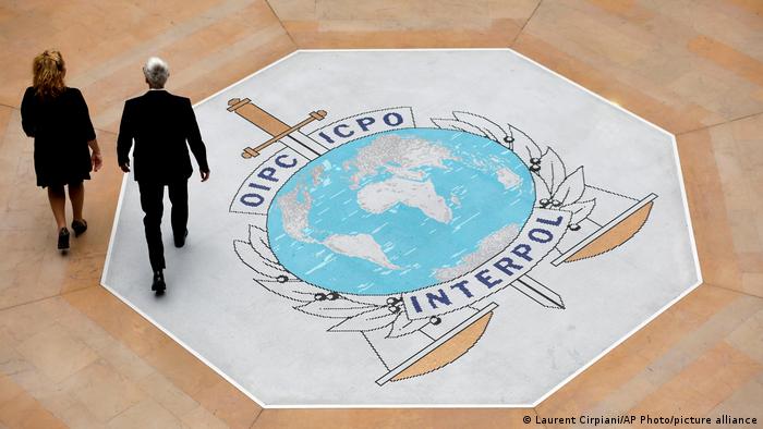 People walk on the Interpol logo at the international police agency headquarters in Lyon