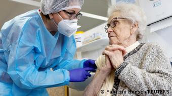 Пожилой женщине делают прививку от коронавируса в немецком доме престарелых