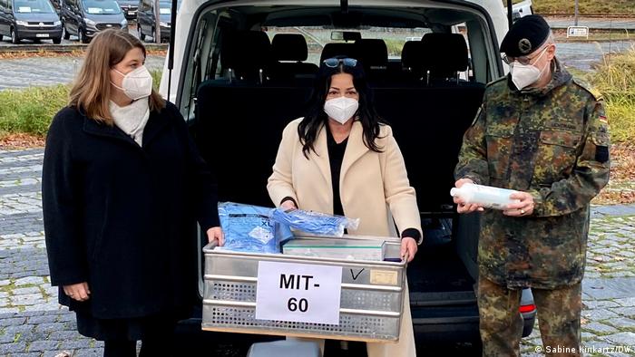 Berlins Gesundheitssenatorin Dilek Kalayci steht mit einer Mitarbeiterin und einem Bundeswehrsoldaten vor der geöffneten Heckklappe eines Transporters und hält eine Kiste mit Impfutensilien in der Hand. Der Wagen gehört zu den mobilen Impfteams in Berlin