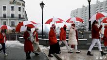 Girls wearing clothes with colors of the former white and red flag of Belarus march in the streets under umbrellas to protest against the Belarus presidential election results in Minsk, on December 16, 2020. (Photo by - / AFP)