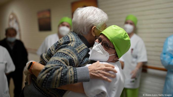 Lydia Navarro, de 84 años, es detenida por un trabajador de la salud momentos antes de recibir una de las primeras vacunas en España en el asilo de ancianos Somontano el 27 de diciembre de 2020